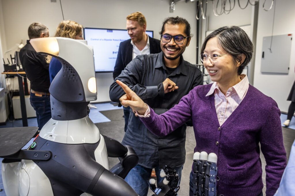 A person touching the face of a humanoid robot.