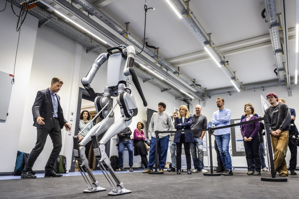 A presentation of a humanoid robot in the foreground, with onlookers in the background.